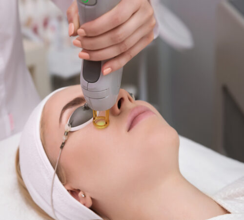 Therapist beautician makes a laser treatment to young woman's face at beauty SPA clinic. Facial laser hair removal epilation procedures. Close up, selective focus.